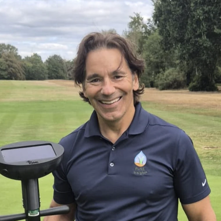 Carmen Magro, PhD CGCS, on turf, holding a TOMi handheld device