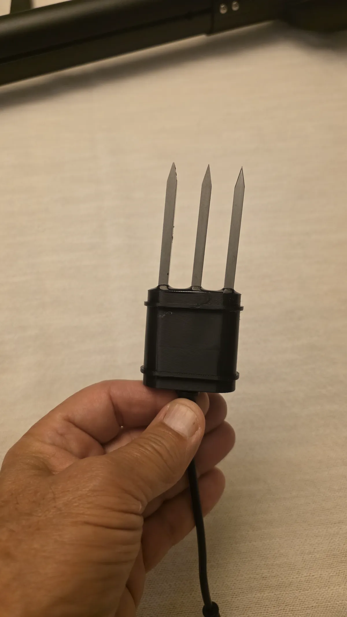 Close-up of the Ceres sensor head held in one hand, showing its three marine-grade stainless steel tines