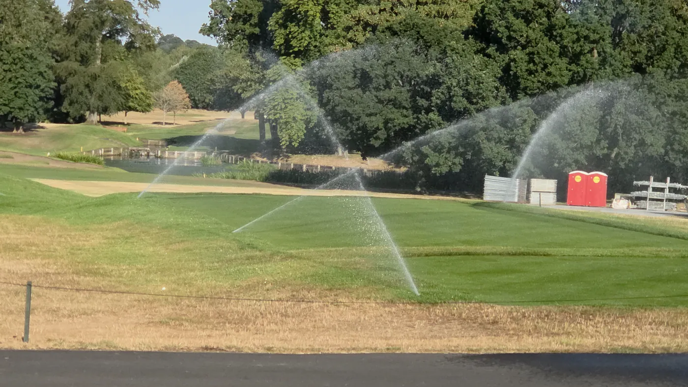 Irrigation heads running across a golf course at dawn